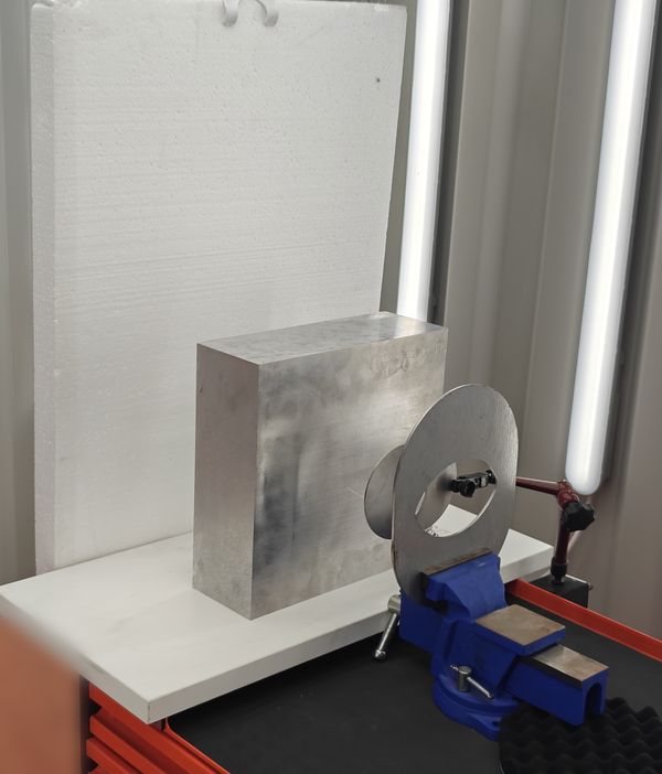 Target stand with a thick aluminium block in front of a foam panel and a steel ring target held in a vice